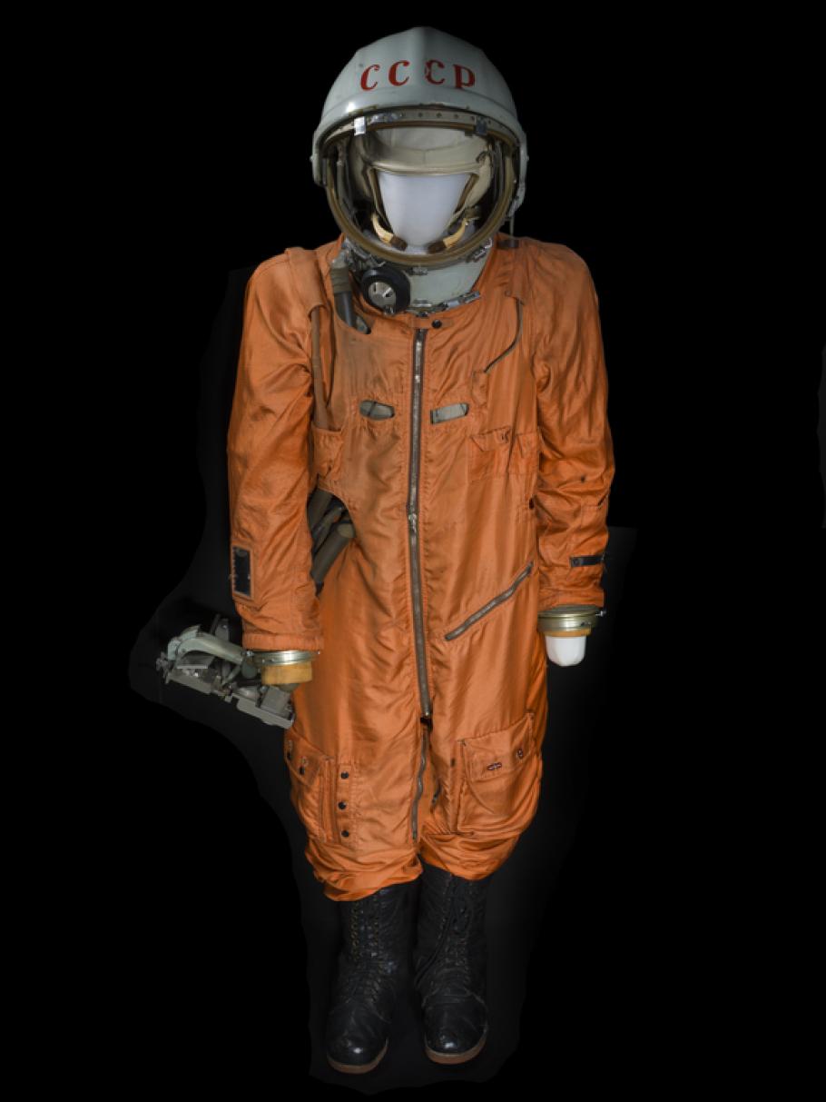 Orange body suit and white helmet with "CCCP" in red lettering across forehead on mannequin 