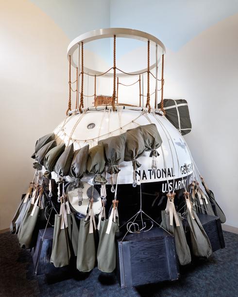 Cabin (gondola) of the "Explorer II" balloon. This is a spherical shape with an open cylinder at the top. There are sandbags attached to the outside. The gondola is painted black and white.