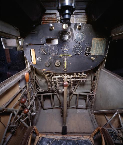 Head-on view, looking directly forward, of cockpit of Ryan NYP “Spirit of St. Louis” , showing forward instrument panel, stick, throttle, rudder pedals, and fuel control system.