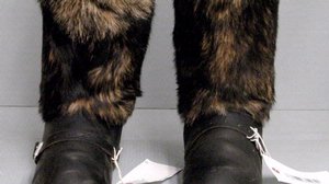 Black leather boots with a silver buckle on the instep and thick black and white fur covering the shaft to the knee.