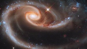 A large bright spiral galaxy absorbing a smaller darker galaxy.