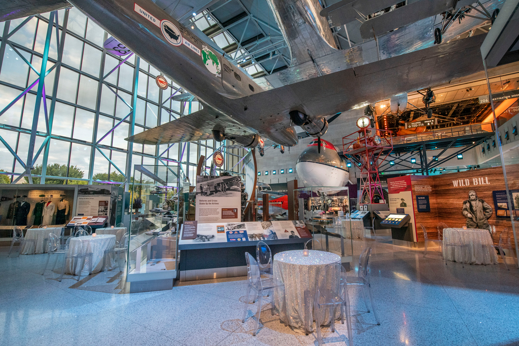 A gallery with planes hanging from the ceiling. It's set up for a special event.