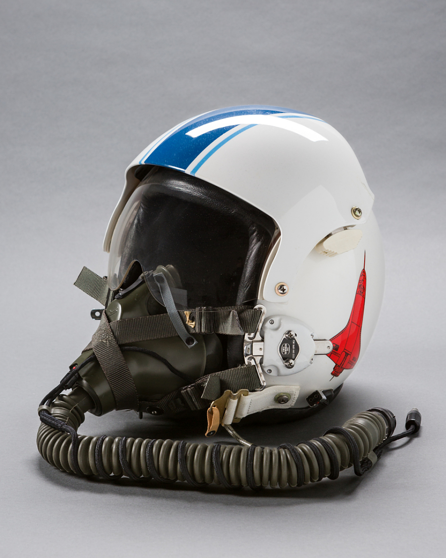 A flight helmet photographed in a studio setting.