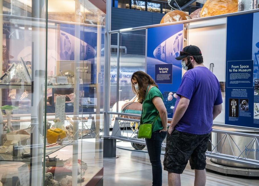 Two people stare down at artifacts in a case.