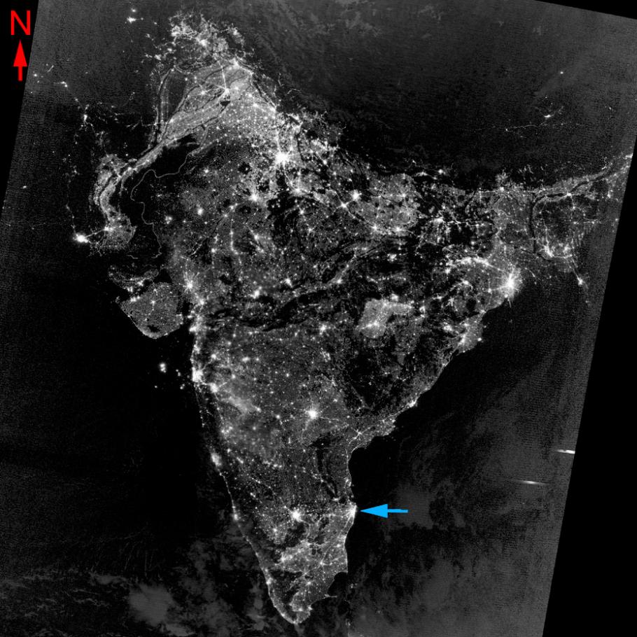 Satellite image of a land mass at night, an arrow points to a spot that is lit up. on the southern half.