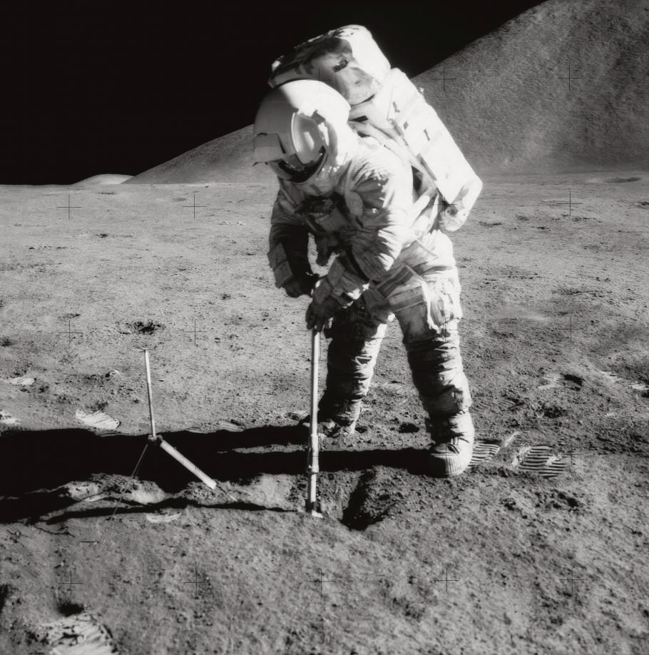 A black and white image of James Irwin digging into the lunar soil during Apollo 15 mission