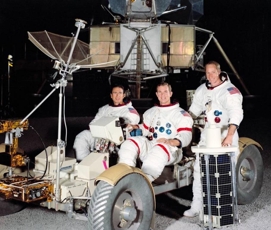Left to right: Jim Irwin, David Scott, and Al Worden pose with mockups of a lunar module (LM) and a lunar roving vehicle (LRV).