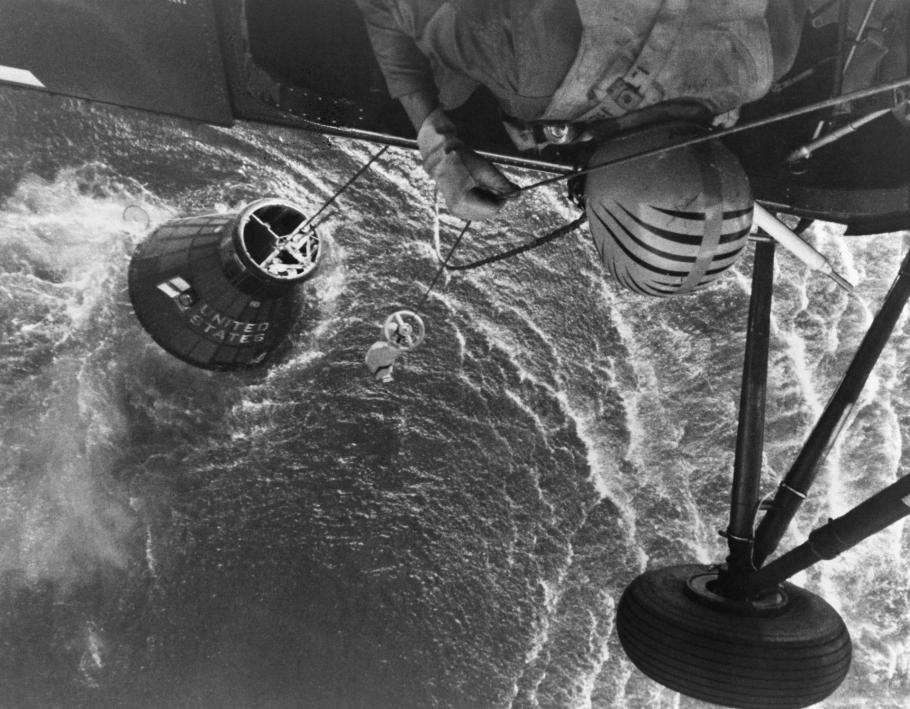view of helicopter attempting to lift spacecraft partially submerged in ocean