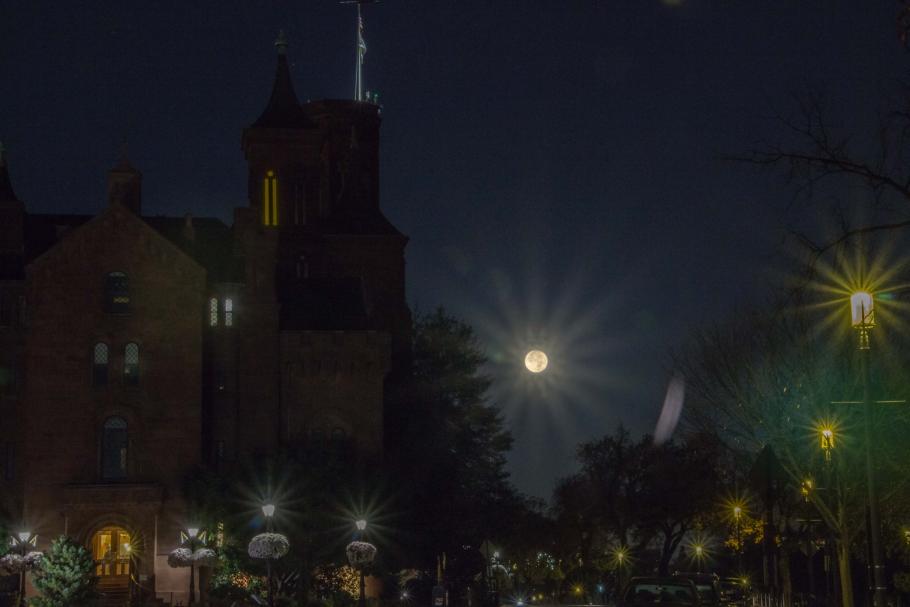 The moon rising with the Smithsonian Castle on the left hand side. 
