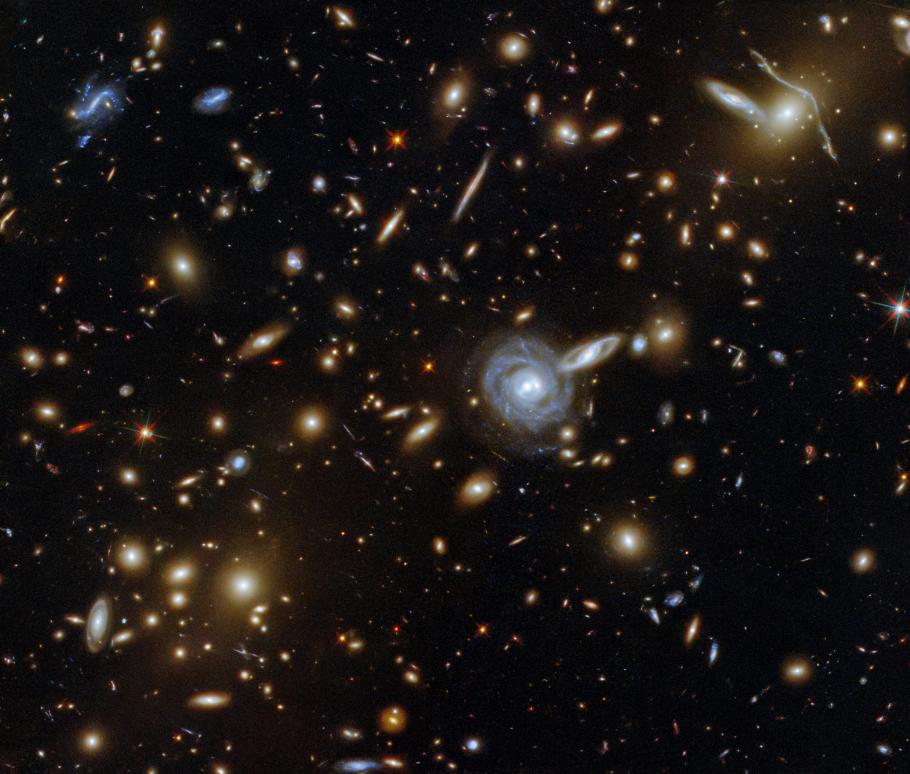 Image of space packed with a cluster of galaxies along with a few foreground stars.