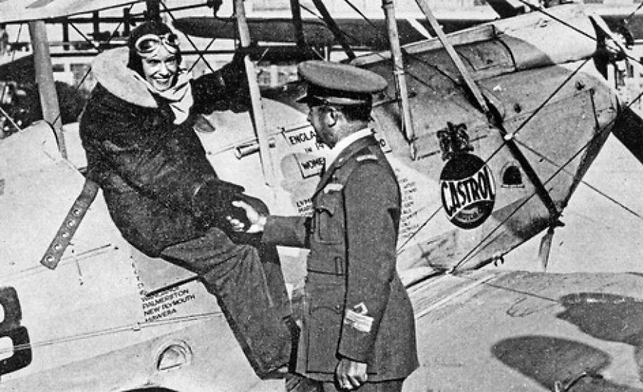 A woman sitting on top of an airplane shakes a man's hand. 