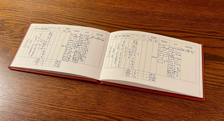 A logbook with writing in blue ink open on a table.