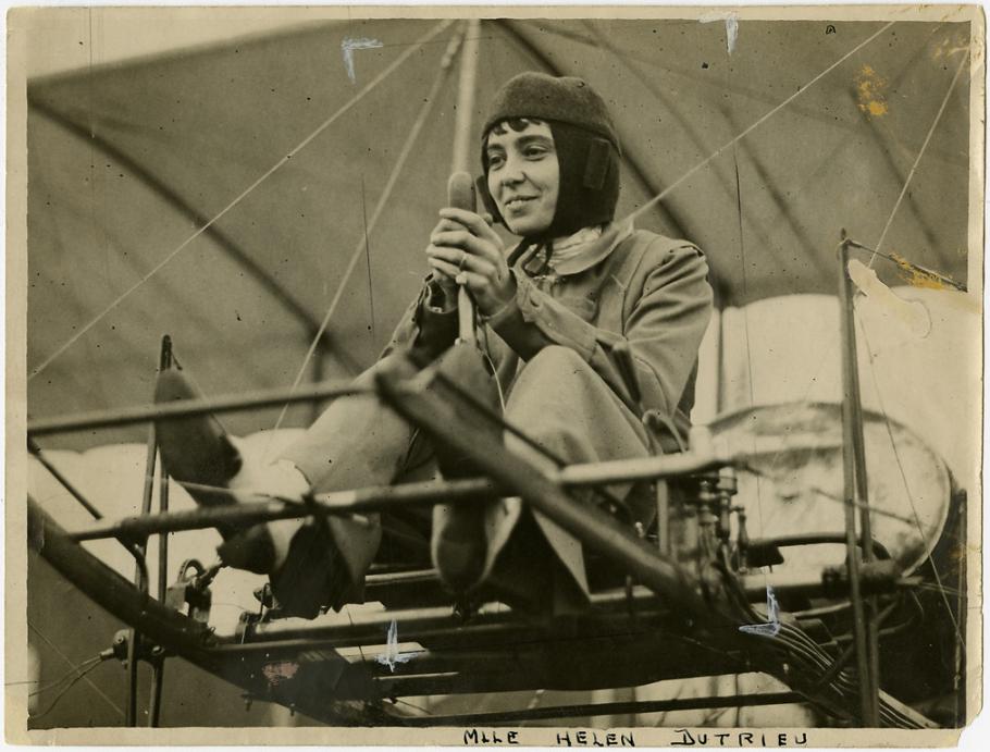 A woman flying a biplane. 