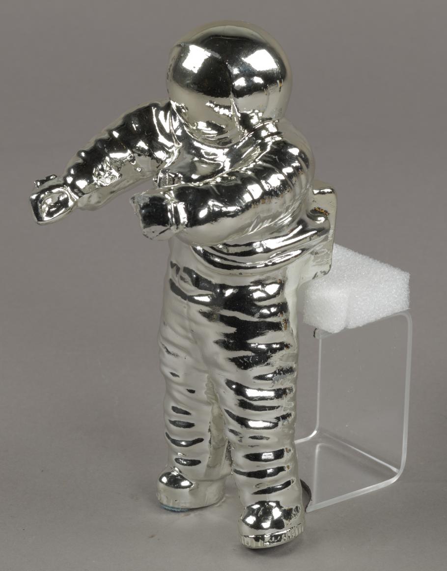A photo of a silver-colored statue that is shaped like an astronaut. 