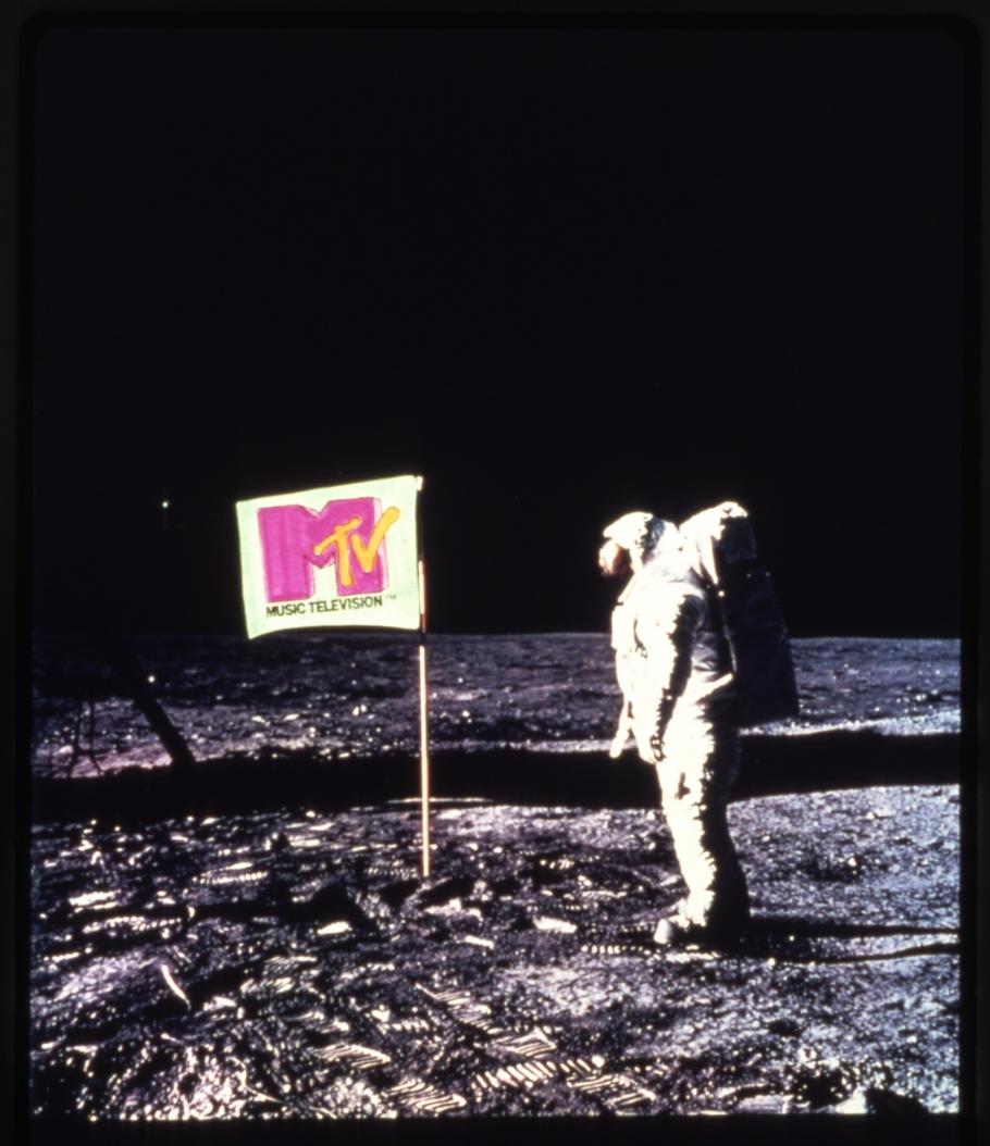A photo of an astronaut on the Moon standing next to a flag with the MTV logo on it.
