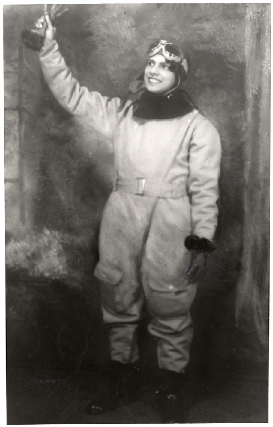 A woman in a flying suit raises her hand in the air.