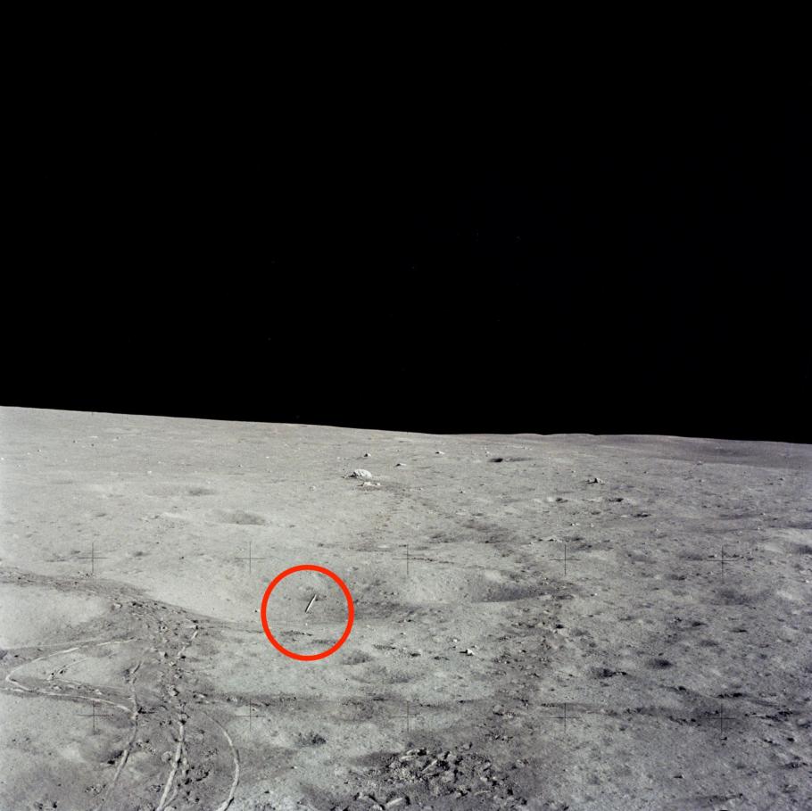 A photo of the surface of the Moon with a red circle around a small circular object, which is a golf ball.