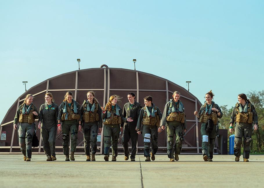 10 female pilots walk together on airfield. 