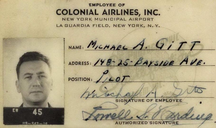 Small black and white card. Text on top: Employee of Colonial Airlines, inc. Headshot photo of a man on right side. He has dark hair and is holding a dark clapboard that reads "EW 45." On the right column are name, address, position: pilot, and two signatures: Michael A. Gitt on top and Lowell S. Harding on bottom.