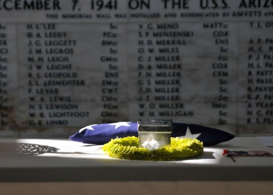 The remains of retired Master Chief Glenn Harvey Lane sit on a table at the USS Arizona Memorial with names written on a wall in the background.