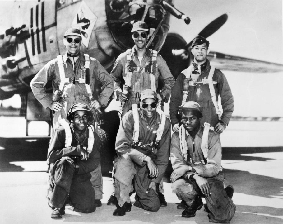 Black and white photograph of six Black men in flight gear (three in front and three in back) posing in front of an aircraft nose.