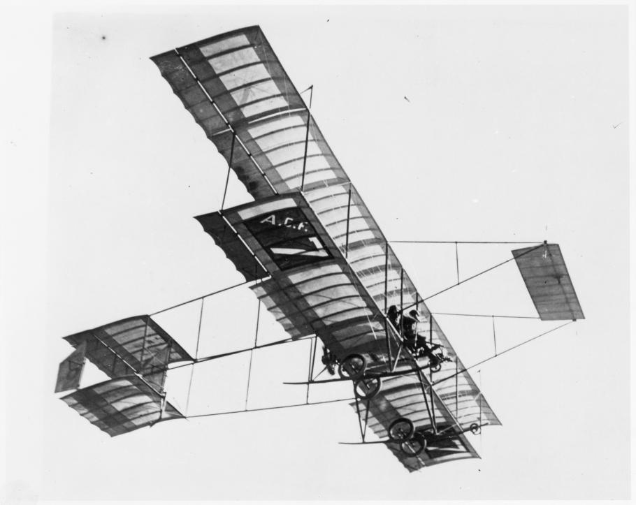 Side view of an airplane in flight. The initials A.C.F. can be seen on the bottom of the plane.