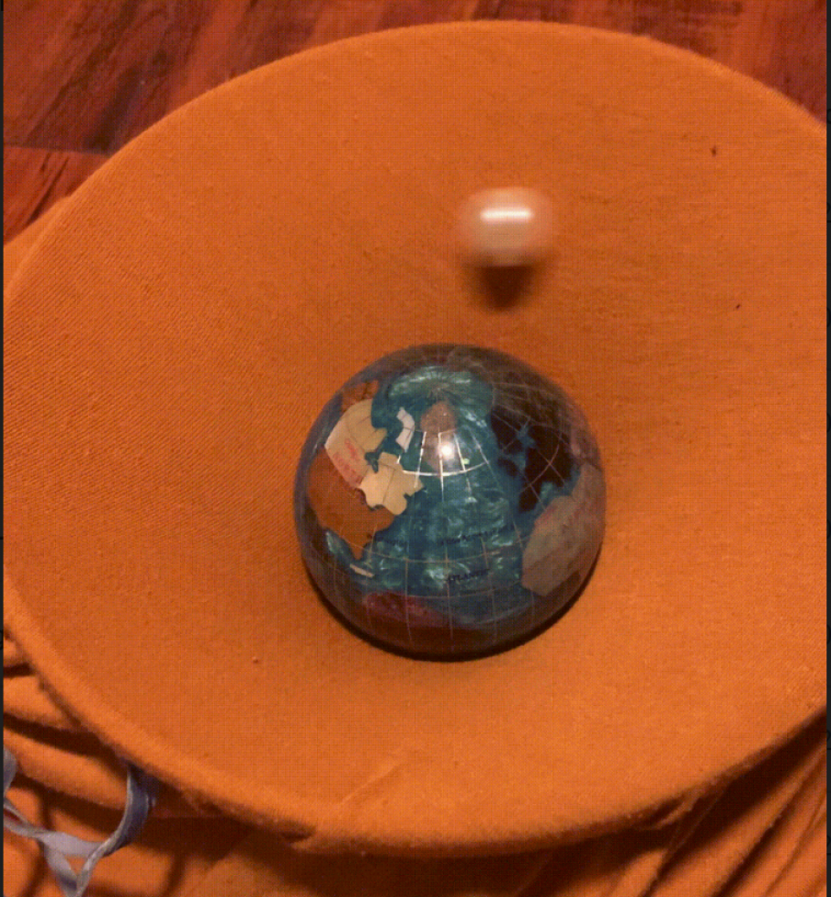 A small ball rotates around a ball made to look like the Earth. 