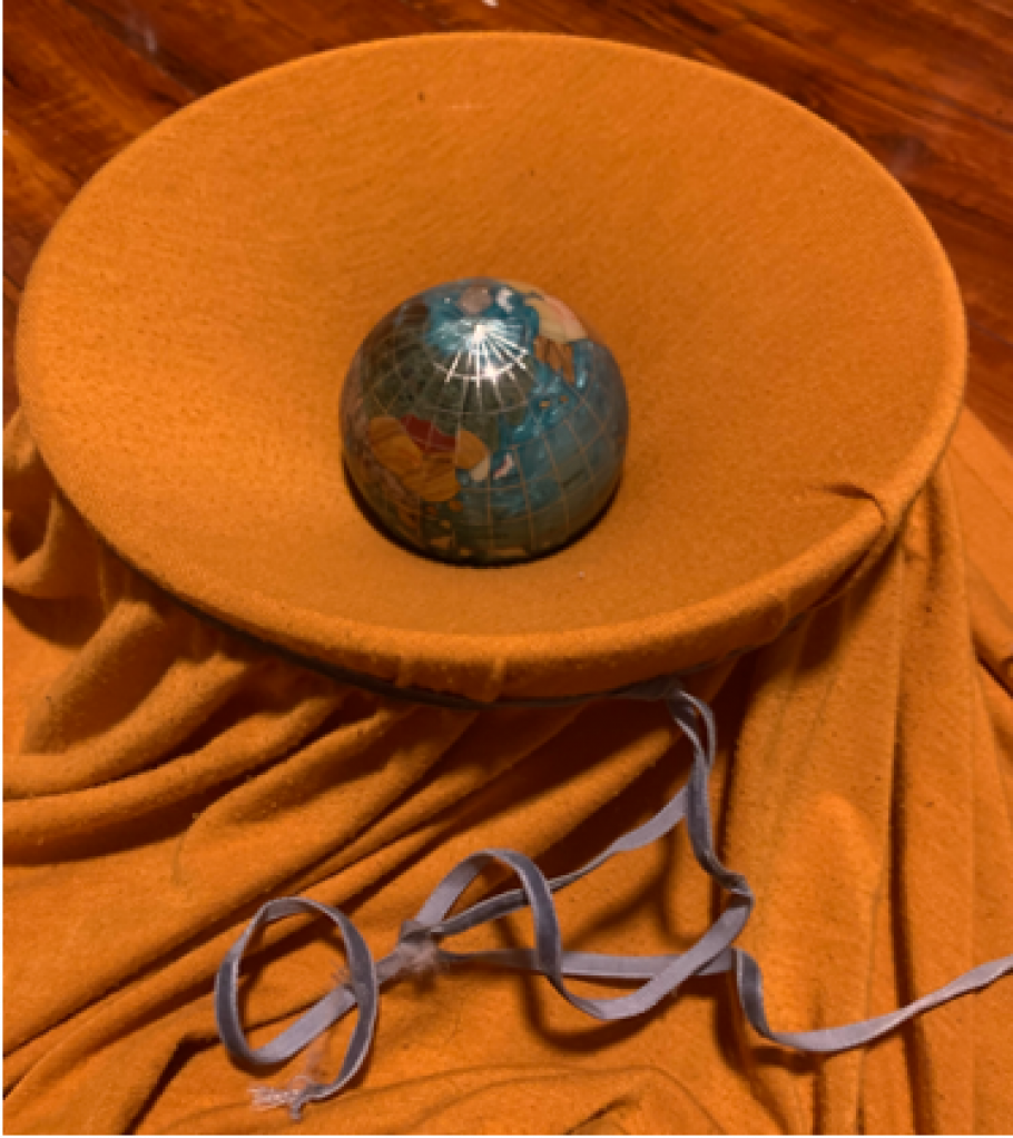 A blanket draped over a bowl, with a ball made to look like Earth perched on top.