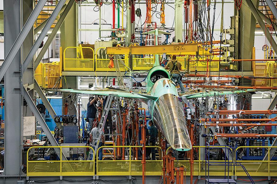 Lockheed Martin X-59 experimental aircraft in factory surrounded metal framing.