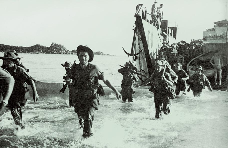 French Marines wade ashore in knee-deep water with transport ship in background