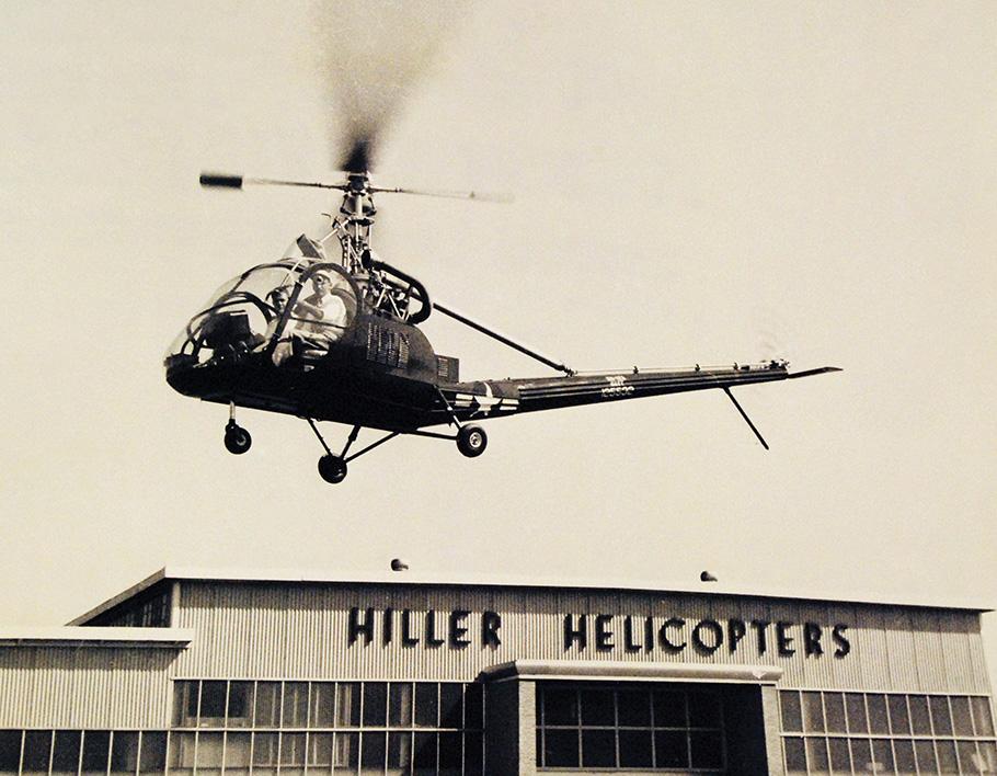 Hiller 360 helicopter hovering above company hangar
