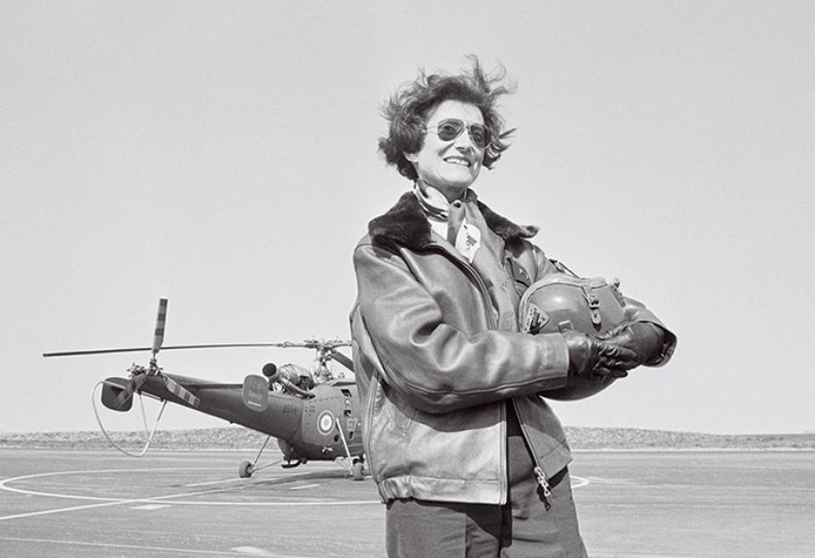 Portrait of French General Valerie Andre holding flight helmet in front of a helicopter