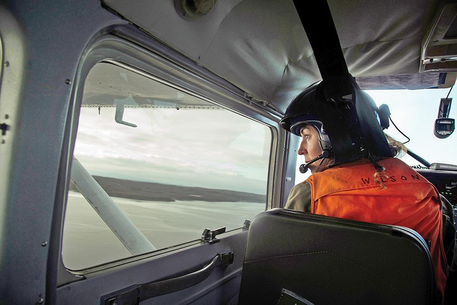 Small aircraft pilot with helmet flies over expanse of water