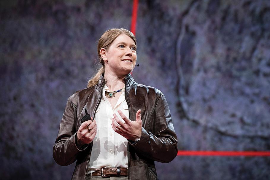 Archaeologist Sarah Parcak in leather jacket gives a TED conference presentation