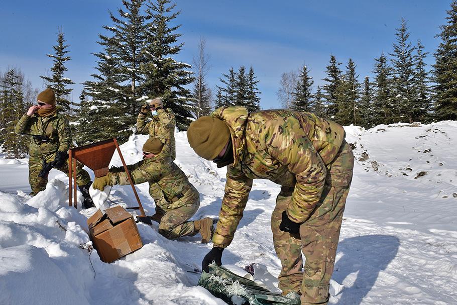 Four air force service members in snowy landscape with pine trees
