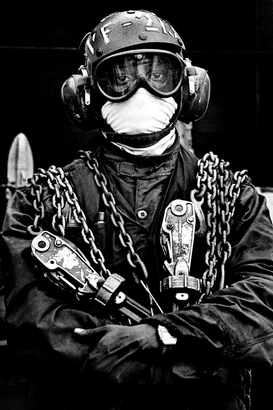 Person with a helmet, goggles, and face covering with chains hanging from their shoulders.