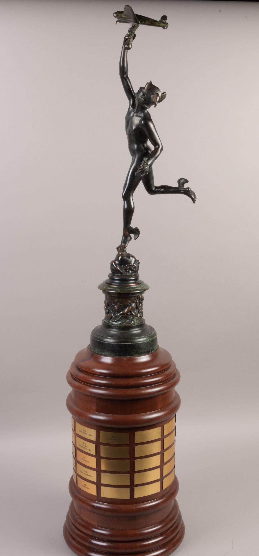 A trophy of a woman holding a plane photographed against a white background.