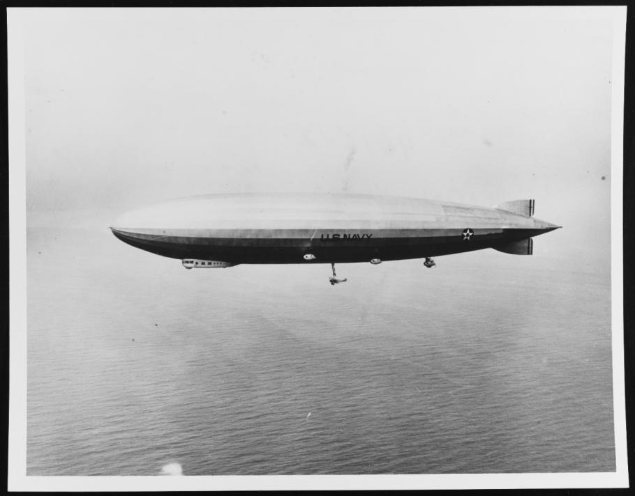 An airship is seen flying above the ocean.