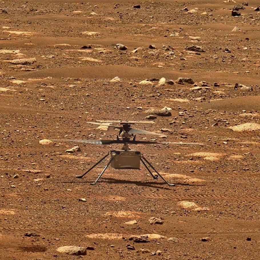 A small helicopter sits at idle on a rocky surface.