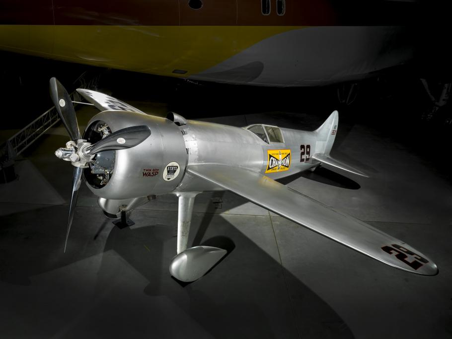 A silver colored, small monoplane featuring a yellow decal on the side that says Champion.