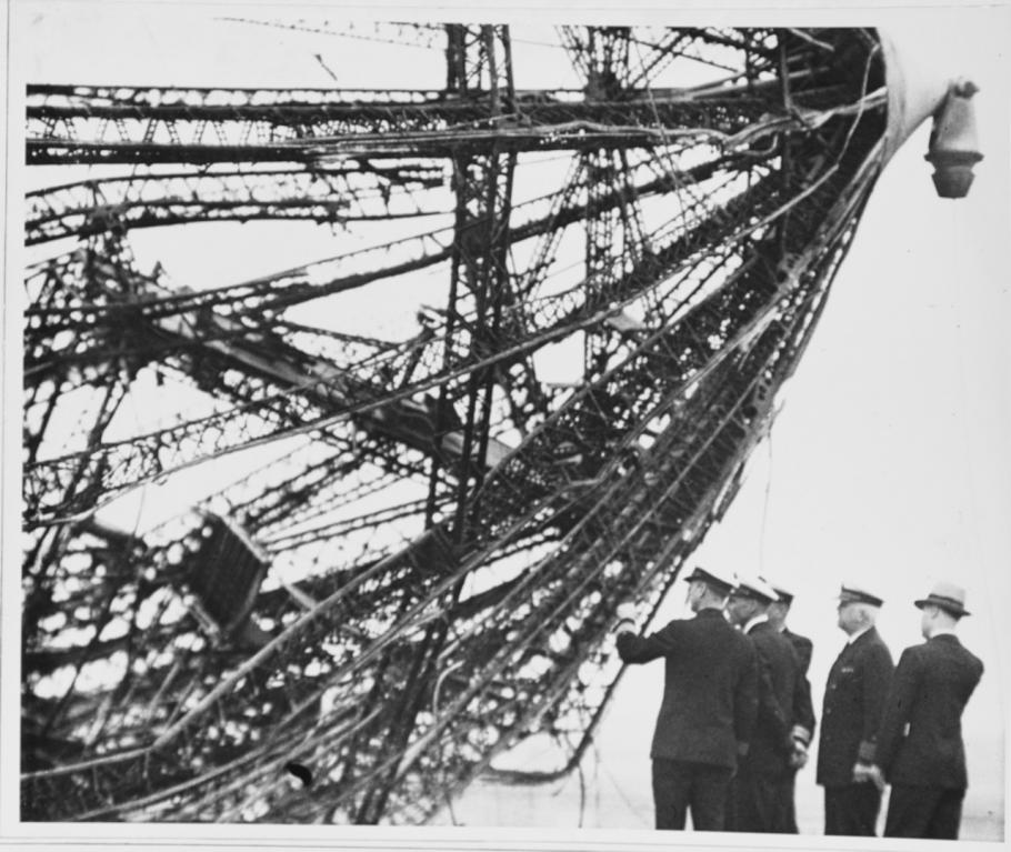 Black and white image of uniformed individuals looking at wreckage from a crash.