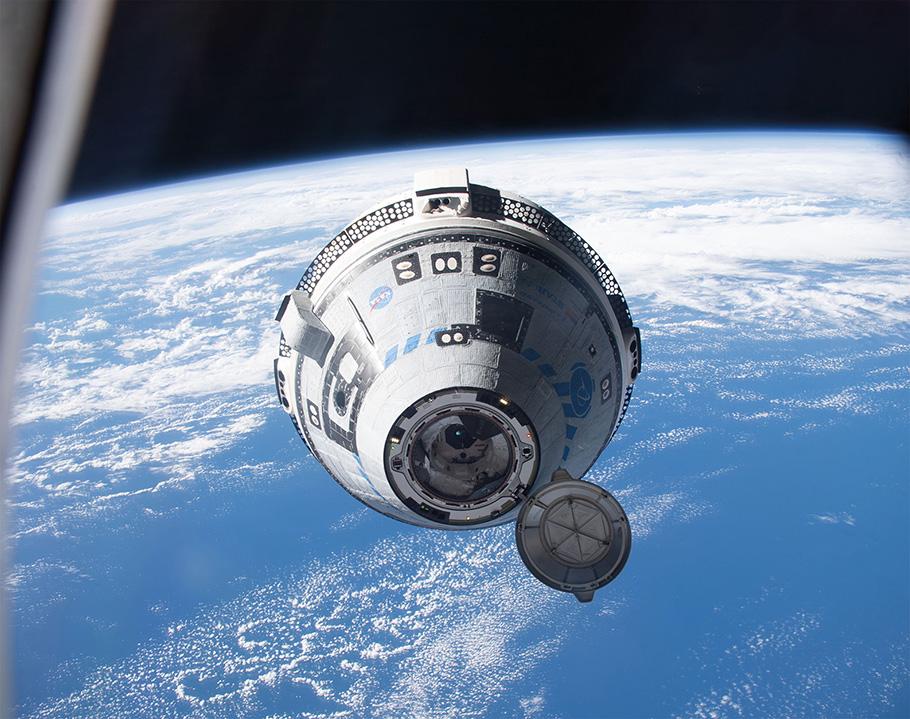 In Earth’s orbit, with our planet filling much of the background, Boeing's Starliner crew ship, which looks like a space capsule, is moving towards the International Space Station, preparing to dock.