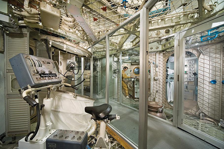 A back-up model of Skylab allows visitors to see the cramped living conditions aboard the space station. An exercise bike appears in the foreground, while a mannequin of an astronaut can be seen dining towards the back.