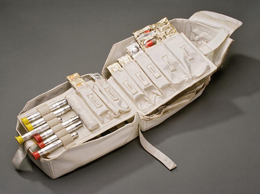 The Apollo 11 command module medical kit is unzipped revealing its contents, which include autoinjectors, capsules, and pills.