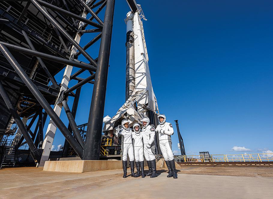The civilian crew of the SpaceX Inspiration4 mission—four people wearing space suits stand in front of a Falcon 9 rocket.