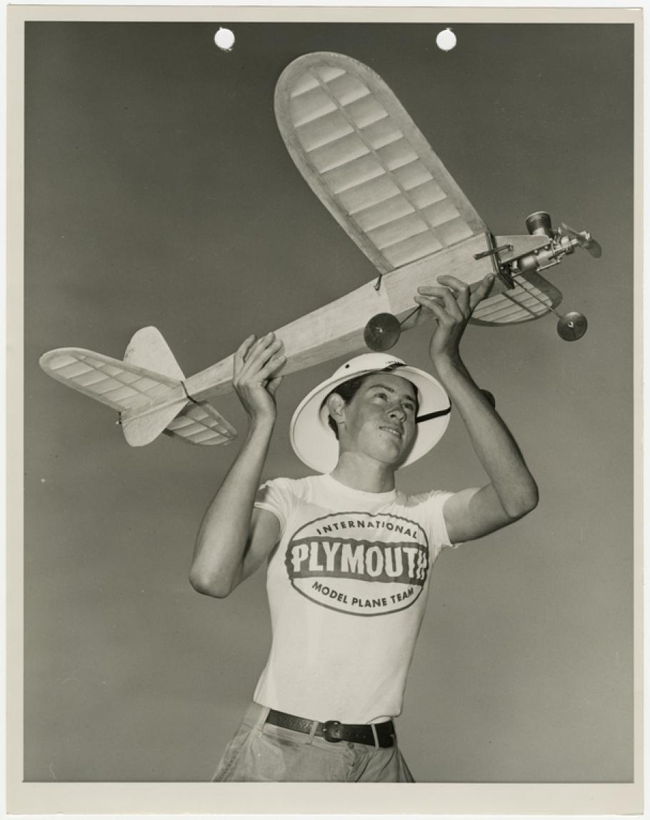 A teenaged-looking boy holds up a large model airplane as if he is about to launch it into the air.
