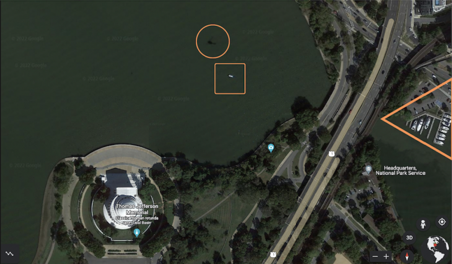 A Google Maps overhead shot of the Jefferson Memorial surrounded by water. In the water there is a dark shadow near a bright white spot. The dark shadow is circled in orange and the white spot has an orange square around it. 