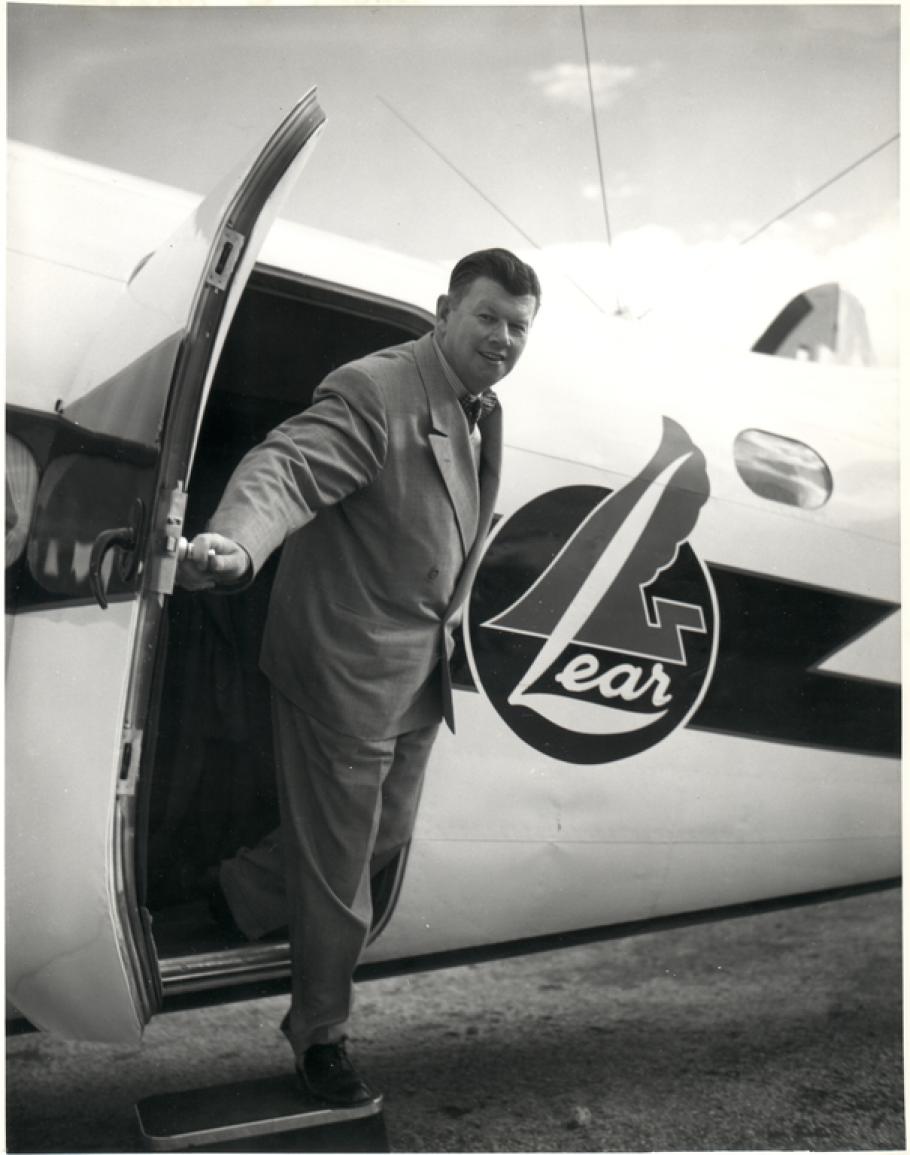 A man stepping out of the door of a small aircraft that says "lear" on its side.