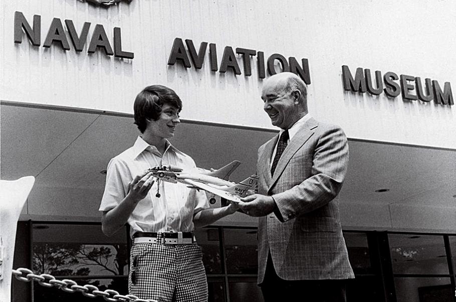 Alternative Text: 16-year-old Al Casby presents his award-winning model of a Cutlass to an official at the Naval Aviation Museum.