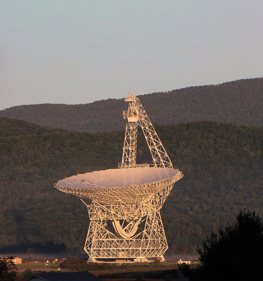 Made of painted white metal, the Robert C. Byrd Green Bank Telescope—with its enormous 100-meter dish—looms in front of a mountain ridge in West Virginia.